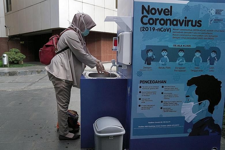 A woman wearing a mask washing her hands at a portable sink outside an office building in Jakarta, Indonesia. PHOTO: BLOOMBERG Workers from PT Pan Brothers Tbk & Group, the largest garment manufacturer in Indonesia with multiple factories across Java