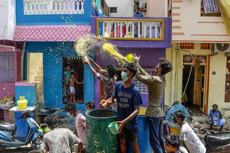Volunteers throwing a mixture of water, neem herb and turmeric as an alleged natural disinfectant on a street in a residential area of Chennai yesterday as India remained in lockdown amid the coronavirus pandemic. PHOTO: AGENCE FRANCE-PRESSE