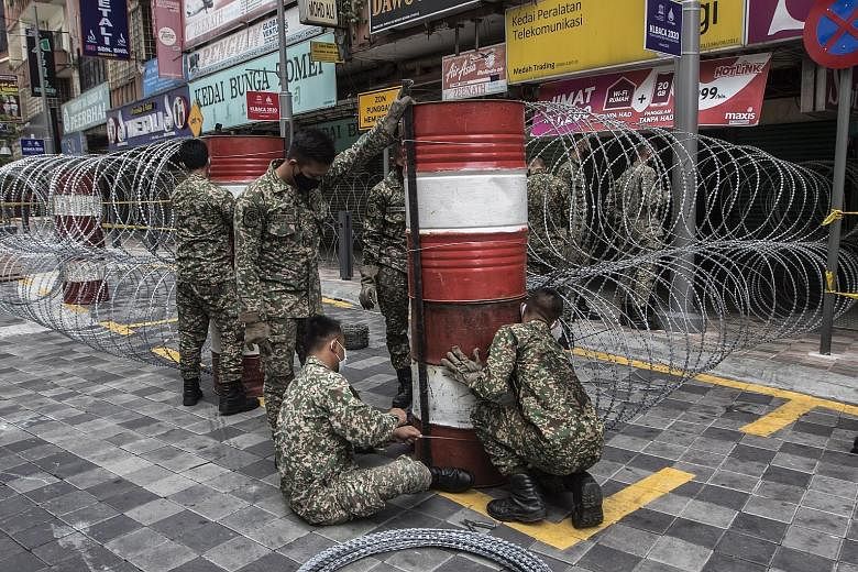 Members of the Malaysian army erecting a barbed wire fence in the Jalan Masjid India area in Kuala Lumpur yesterday. Two buildings in the area were placed under an enhanced movement control order after 15 cases of coronavirus infections were detected