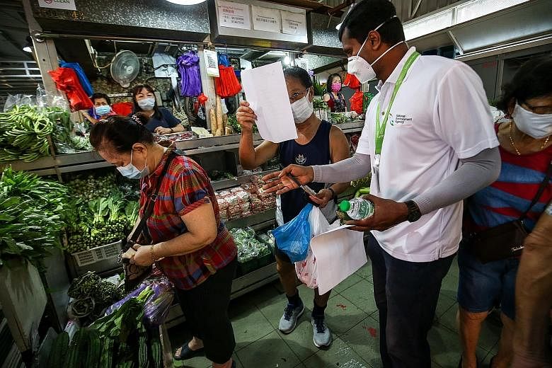 A National Environment Agency officer serving a written advisory to a customer at Jurong West 505 Market for not observing safe distancing requirements yesterday. The Ministry of Environment and Water Resources said 10,000 advisories were issued over