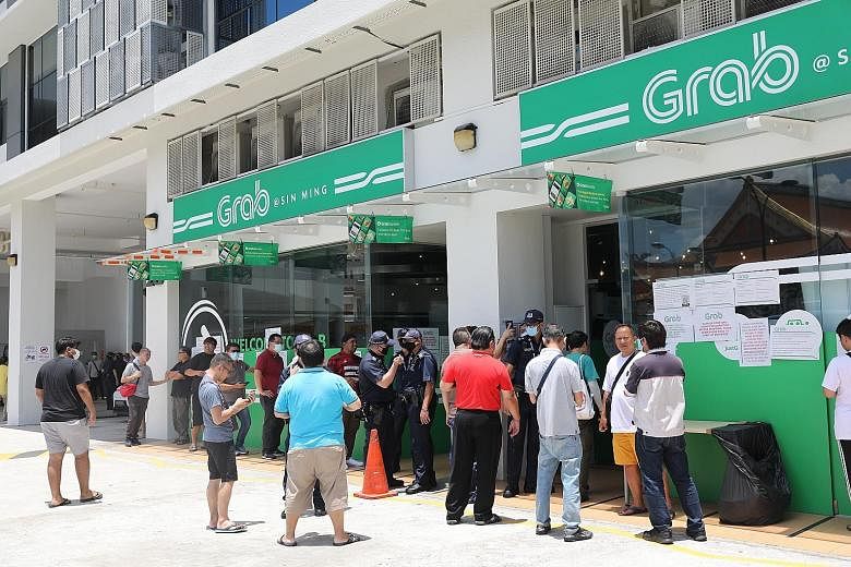 Private-hire drivers outside Grab's office in Sin Ming Lane yesterday, with a few police officers maintaining order. In an update later, Grab said eligible drivers would be able to start delivering food and parcels by the end of the day, even if they