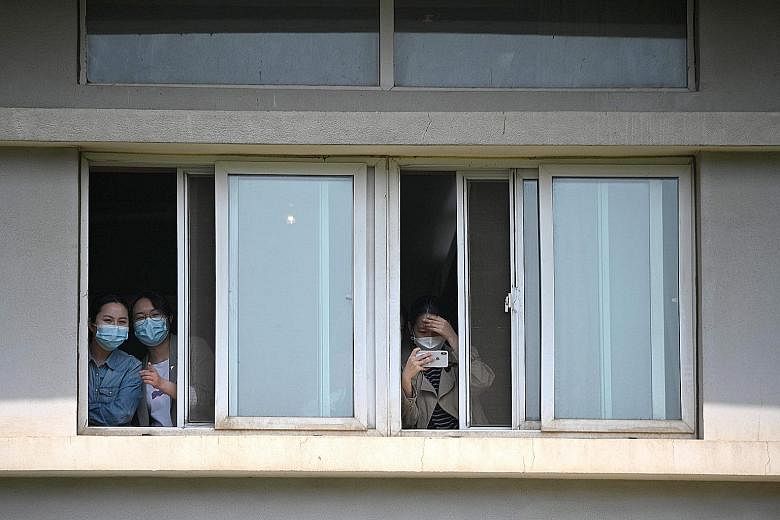 People with face masks peeking from windows of the Jinyintan Hospital in Wuhan, China's central Hubei province, yesterday. Dubbed "ground zero" at the height of the coronavirus outbreak in the city, Jinyintan is the only specialised infectious diseas