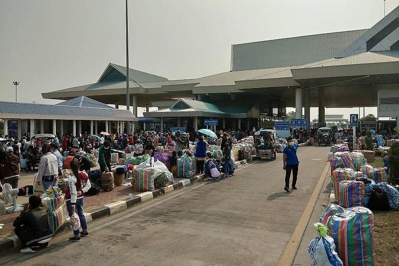 People with their belongings lining up at the immigration post by the second Thai-Lao Friendship Bridge in Mukdahan, waiting to cross into Laos on March 23. PHOTO: AGENCE FRANCE-PRESSE A supermarket employee in Bangkok disinfecting trolleys. Supermar