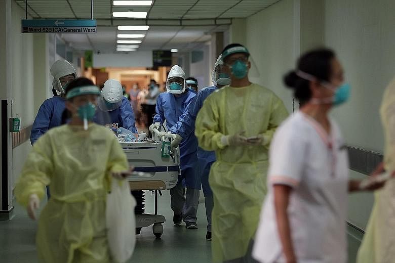 Medical staff in full personal protective equipment with a suspected Covid-19 patient last month. When the coronavirus epidemic started in Singapore, the Ministry of Health's chief health scientist Tan Chorh Chuan asked the National University of Sin