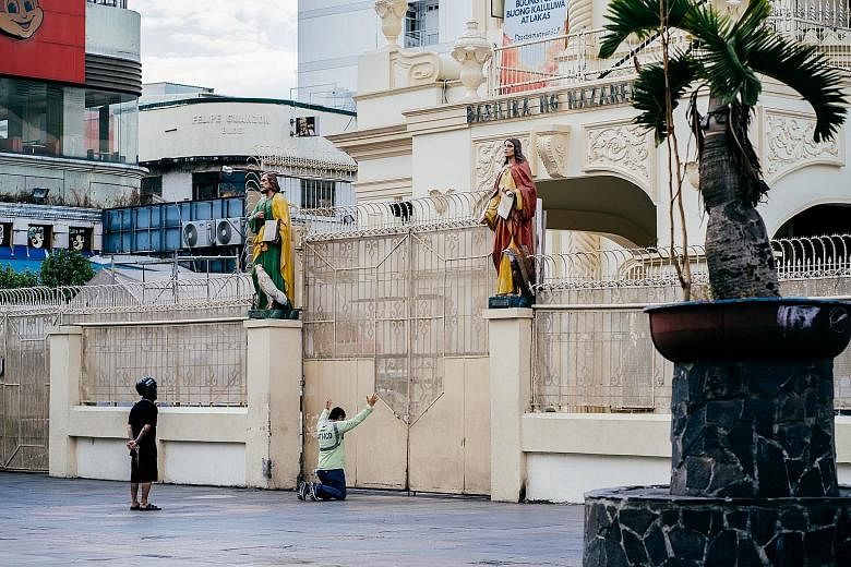 Devotees outside the closed gates of Quiapo Church in Manila yesterday, which was Good Friday. Across the Philippines, churches and shrines are shut and empty because of the sweeping lockdown that aims to keep the spread of the coronavirus in check. 