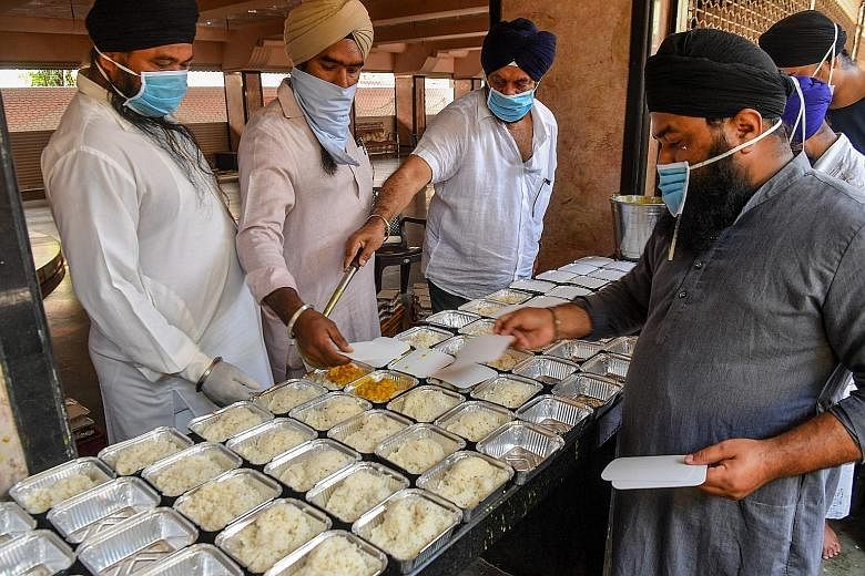 Sikh community volunteers preparing food to be distributed at a temple in Mumbai. Across India, people are coming together to help feed the poor and less privileged. PHOTO: AGENCE FRANCE-PRESSE Labourers and daily-wage workers waiting to receive food