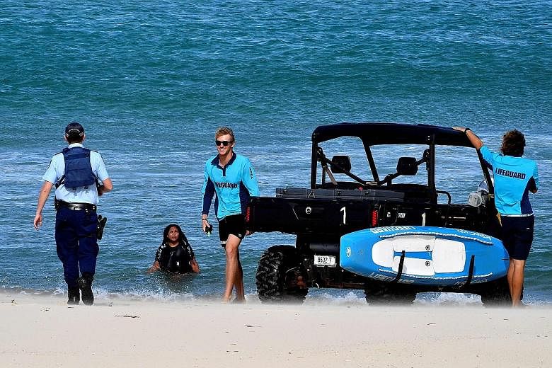 A police officer telling a woman to get out of the water at Sydney's Bondi Beach yesterday. The beach has been closed as part of measures to rein in the spread of the coronavirus. Social distancing rules vary across Australia's states and have caused