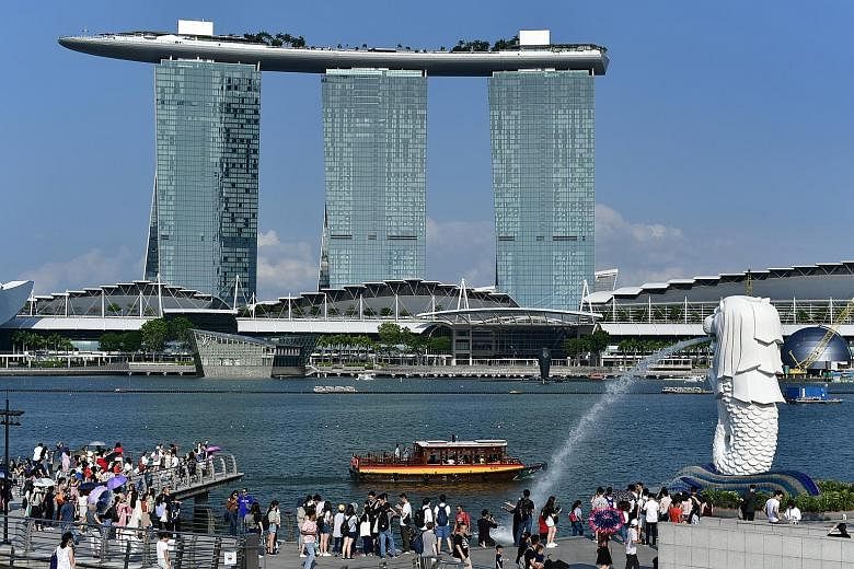 Tourists at the Merlion Park (left) in July last year, with Marina Bay Sands in the background, and what the area looked like on the second day of the circuit breaker in Singapore earlier this month. To contain the spread of the coronavirus, many cou