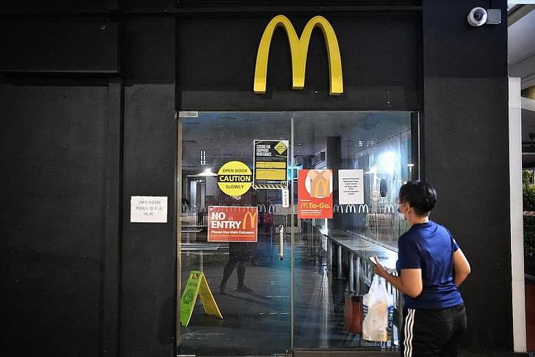 A passer-by reading the closed-for-cleaning sign at the McDonald's outlet in Geylang East Central yesterday. It was among the four outlets where five employees were diagnosed with Covid-19. ST PHOTO: ARIFFIN JAMAR
