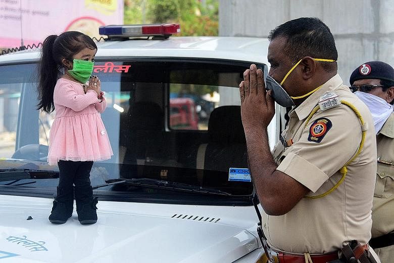 The world's smallest living woman, Ms Jyoti Amge, greeting a police officer in Nagpur yesterday as she urged citizens to stay at home during India's government-imposed nationwide lockdown.