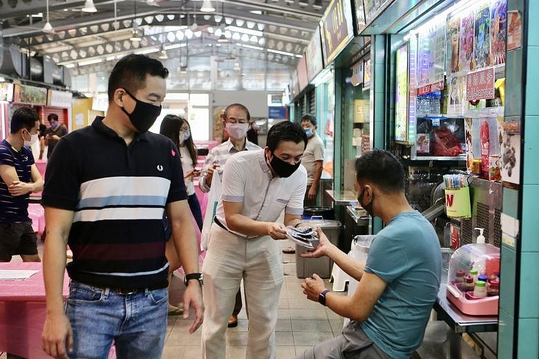 Tanjong Pagar GRC MP Chia Shi-Lu distributing reusable face masks to a hawker at Alexandra Village Food Centre on Sunday. With him is Colonel Eric Chua (in striped T-shirt).