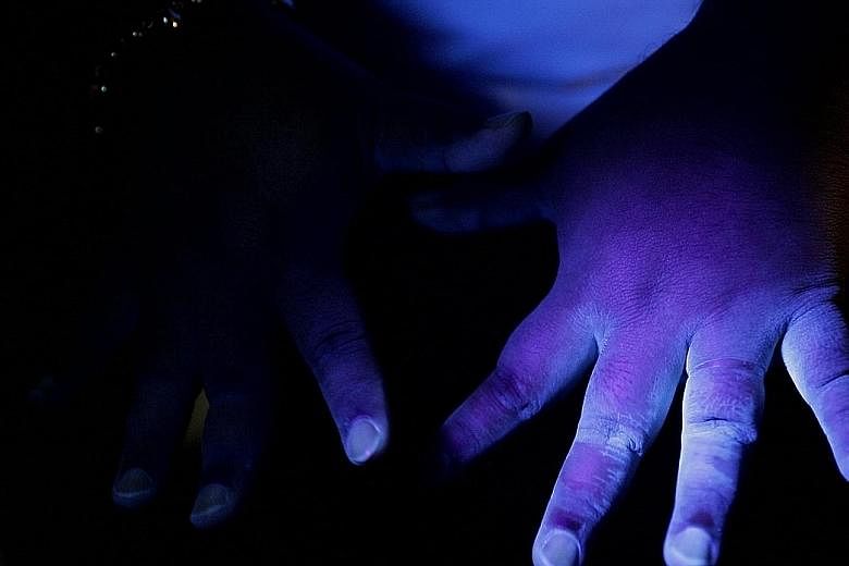 Under the UV light, Person C's hands are much less stained and found to be clean after they were washed with antibacterial soap using a seven-step technique. Seen under UV light in the experiment, Person B's hands have some visible stains - indicatin