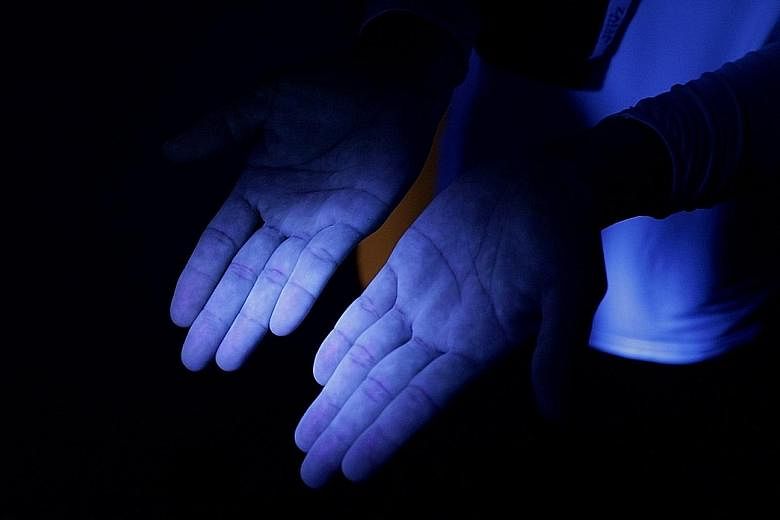 Under the UV light, Person C's hands are much less stained and found to be clean after they were washed with antibacterial soap using a seven-step technique. Seen under UV light in the experiment, Person B's hands have some visible stains - indicatin