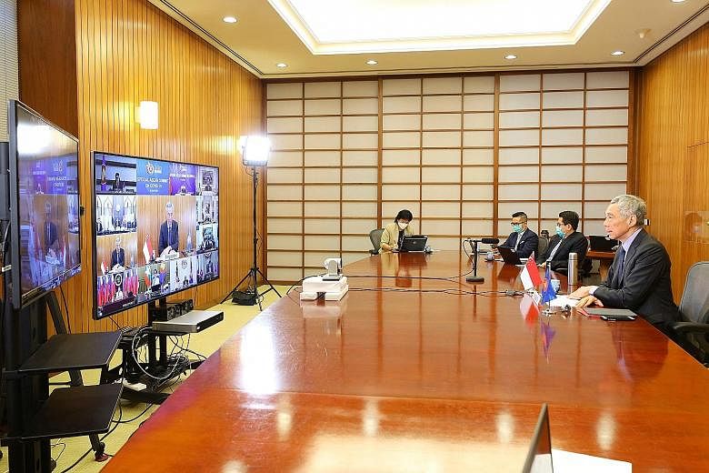South Korean senior officials, including Foreign Minister Kang Kyung-wha (left), watching the teleconference of the summit at the presidential office Cheong Wa Dae in Seoul yesterday. Prime Minister Lee Hsien Loong attending the virtual summit to dis