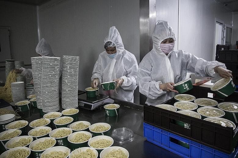 Workers wearing protective gear at a noodle factory in Wuhan, Hubei province. China's growth this year is set to stumble to 2.5 per cent, its slowest annual pace in nearly half a century, according to a Reuters poll.