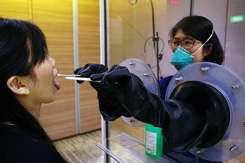 Throat swabs being done with SG Safe (left), a transparent booth system, and SG Shield, which gives healthcare workers added protection. PHOTOS: SGH