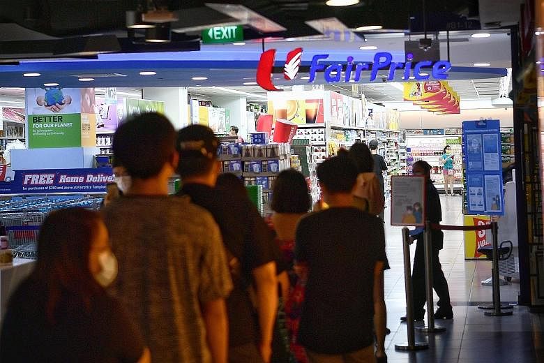 People waiting to enter FairPrice in Tampines Mall yesterday evening, as part of crowd-control measures. A National Environment Agency officer at Holland Drive Market and Food Centre yesterday morning, helping to ensure that the shoppers there were o