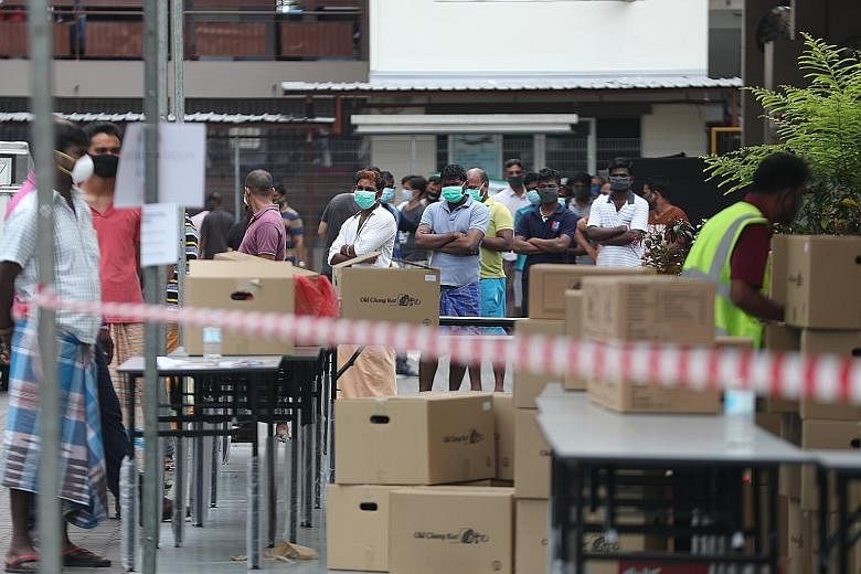 Migrant workers who are residents of Jurong Penjuru Dormitory 1 queueing to collect food yesterday. The dormitory is among those with a cluster of Covid-19 cases. Medical posts are being set up at all 43 purpose-built dormitories and other locations,