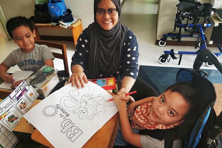 Madam Nur Hidayah Shahrudin helping her seven-year-old twins, Qays and Rizq (far right), with home-based learning. She also does daily therapy exercises with Rizq, who has cerebral palsy.