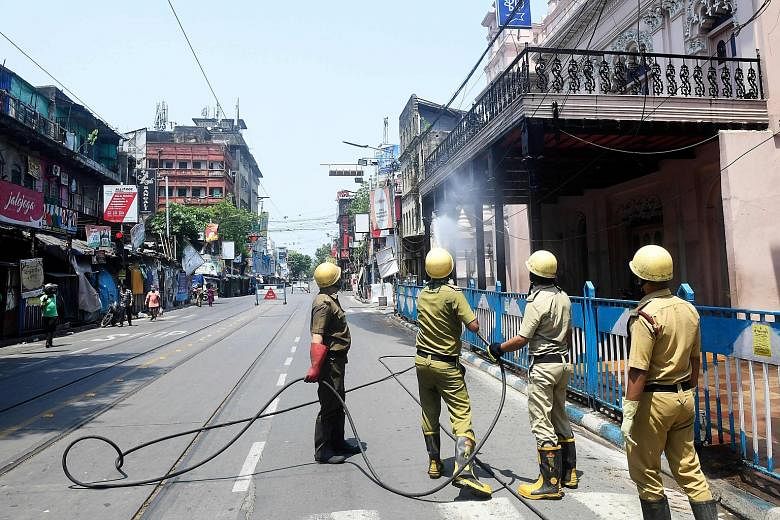 Firefighters spraying disinfectant on the exterior of a theatre in Kolkata in West Bengal state yesterday as a preventive measure against the coronavirus. India, which is under a national lockdown, now has over 16,000 cases of Covid-19. PHOTO: AGENCE