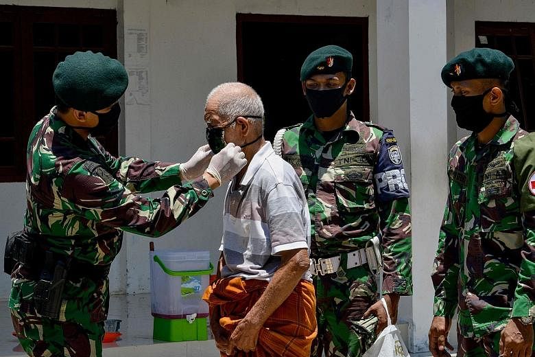 An Indonesian soldier putting a mask on a man in Darul Imarah, Aceh, yesterday. PHOTO: AGENCE FRANCE-PRESSE