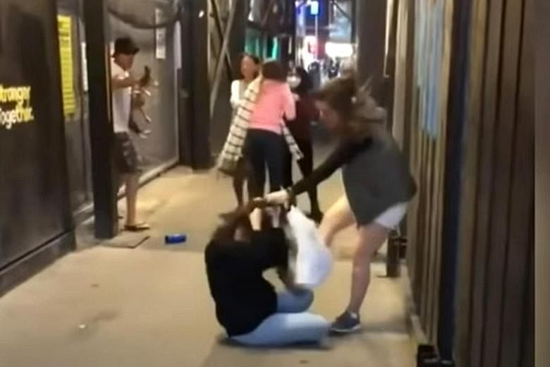 Above and below: Screengrabs of a video on social media showing a woman grabbing one student by the hair and punching her repeatedly on the head before dragging her to the ground and kicking her. The attacker's accomplice, in a pink jacket, is seen p