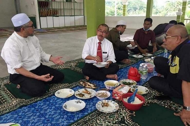 Malaysia's Deputy Rural Development Minister Abdul Rahman Mohamad (in blue shirt) says a gathering where a cake was presented to him by a group of people was unplanned and not meant to violate the country's movement control order. The photos sparked 