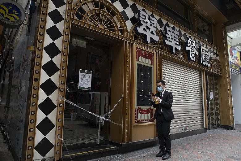 A masked man outside a shuttered restaurant in Hong Kong yesterday. A rule on mandatory use of masks remains in place in the city.