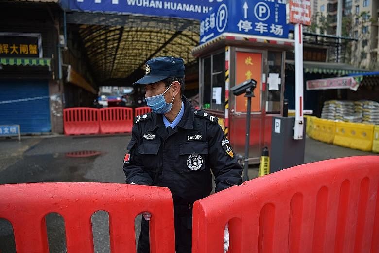 A police officer outside the Huanan Seafood Wholesale Market in Wuhan in January. The outbreak of the coronavirus has been traced to the market which also sells live animals. PHOTO: AGENCE FRANCE-PRESSE