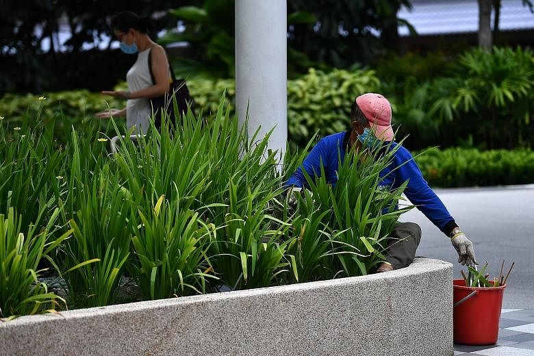 A landscape worker pruning plants outside Heartbeat @ Bedok yesterday. The cut in the number of essential services would reduce the proportion of the workforce commuting to work from 20 per cent to 15 per cent.
