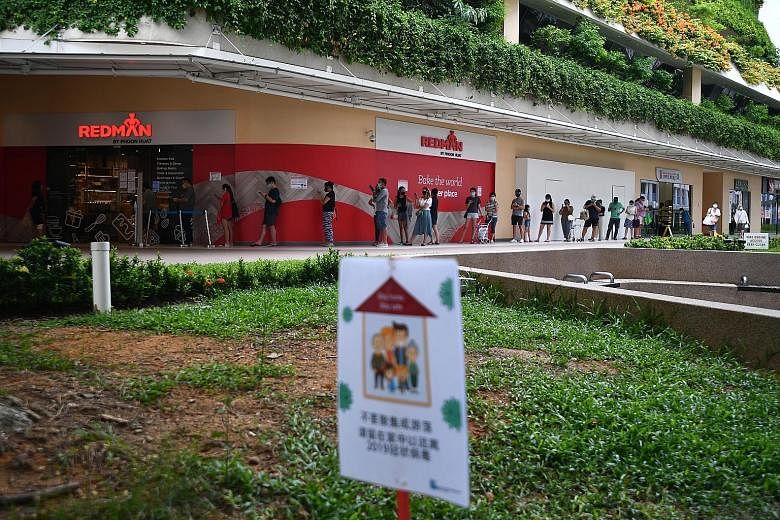 A long queue of shoppers waiting to enter a RedMan by Phoon Huat store at Heartbeat @ Bedok yesterday. The number of new cases in the general community has decreased, from an average of 34 cases a day in the week before, to an average of 25 a day in 
