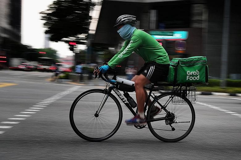 A GrabFood delivery partner in the city area earlier this month. With people staying in and more ordering food, it is not difficult for riders to make about 20 trips a day.