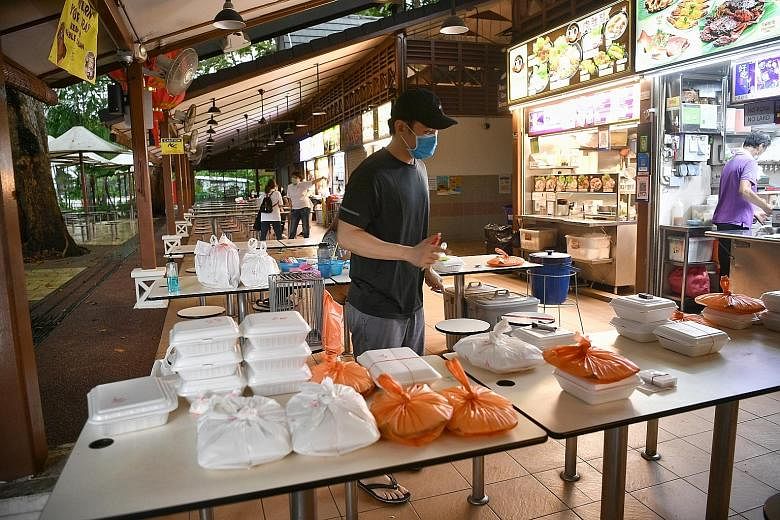 Mr Kelvin Foo, the owner of Hai Yan BBQ Seafood, managing delivery orders on Friday. The stall, at Newton Food Centre, uses four tables to split up the deliveries bound for different locations. This way, delivery personnel are kept at least 1m apart 