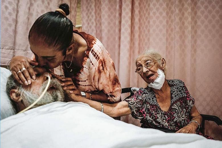 In a photo taken before the circuit breaker began, an HCA Hospice Care patient, Madam Niranjan (at right), and her daughter say goodbye to Madam Niranjan's son before his death. PHOTO: HCA HOSPICE CARE