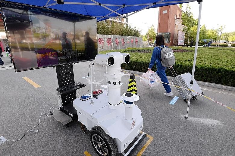 A student in Handan, China's Hebei province, walking past a robot that takes body temperature at the school entrance last week. Schools in Beijing reopen their doors to final-year senior high students today. The students must have their faces scanned