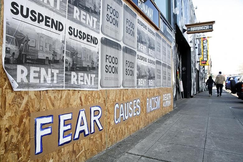 A sign with the words "Fear causes racism" on a boarded-up business in Seattle's Capitol Hill neighbourhood. Experts have pointed out that throughout history, immigrants and minority communities have been blamed for and attacked during disease outbre