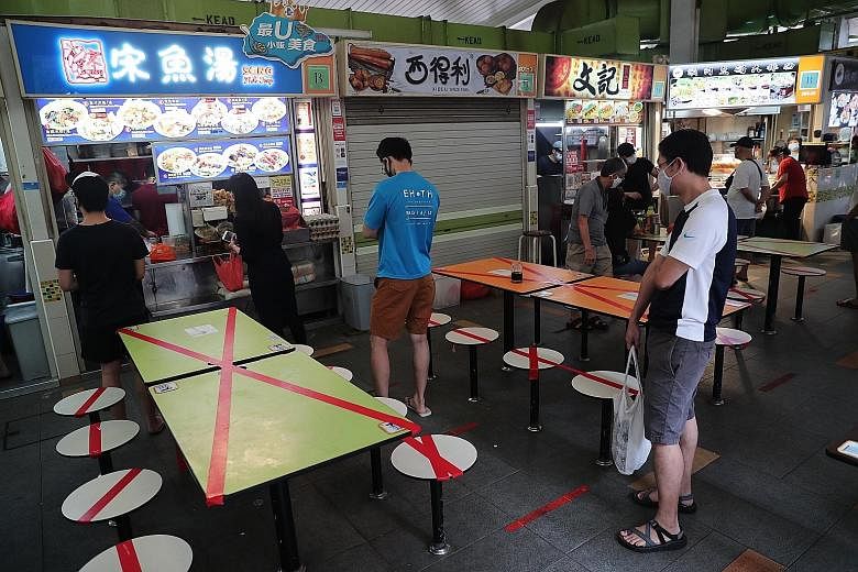 Customers observing safe distancing at Block 448 Clementi Market and Food Centre yesterday morning. On Sunday, about 70 people were caught breaching safe distancing measures, down from more than 240 the Sunday before.