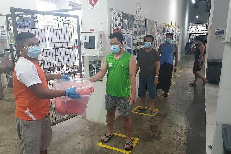 Safe distancing markers in place at local construction firm Woh Hup's dormitory in Joo Koon to ensure that food collection can be done safely. Workers at the Joo Koon dormitory keeping their distance from one another while waiting to have their tempe