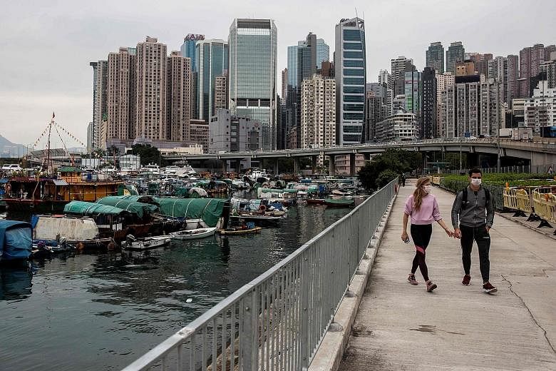 A masked couple strolling along Victoria Harbour's promenade in Hong Kong. The coronavirus outbreak is the final straw for the city's hotel industry, which has already been battered by a year of political unrest. Room revenues are badly hit by travel