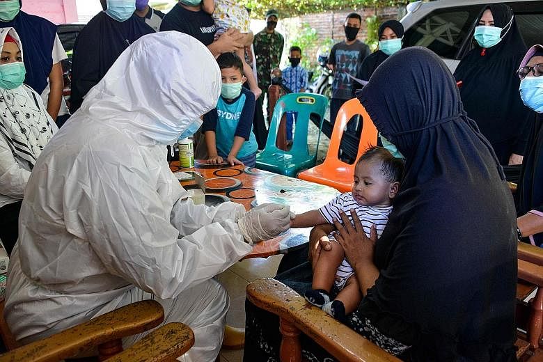 A medical worker taking a blood sample from a child in Banda Aceh, as part of mass testing for the coronavirus. Indonesia has been hampered by a shortage of testing equipment and the chemicals needed for them, as well as specialists required to condu