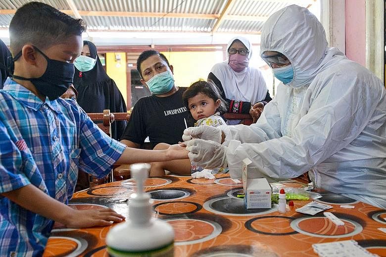 A boy having his blood sample taken as officials conducted Covid-19 testing on Wednesday for residents living close to a boarding house in Banda Aceh where foreign students had reportedly fallen ill. The Indonesian government last week announced a ba