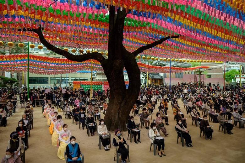 Worshippers wearing face masks attending a prayer ceremony entitled "Overcoming and healing the Covid-19 coronavirus", while marking Buddha's birthday at the Jogye Buddhist Temple in Seoul yesterday. South Korea's success in containing the outbreak -