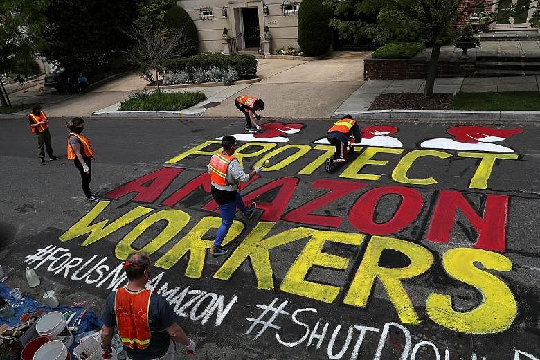 Activists painting a message for Amazon founder and CEO Jeff Bezos on the street outside one of his residences in Washington last month. PHOTO: REUTERS
