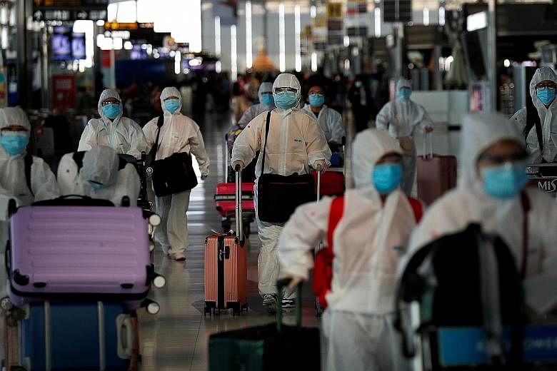 Chinese passengers wearing protective suits at Suvarnabhumi Airport in Bangkok before boarding a repatriation flight last week. The International Air Transport Association has described the plunge in global passenger traffic as the "largest decline i