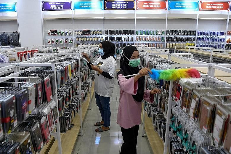 Workers at a mobile phone accessories shop in Terengganu preparing yesterday to resume business today. Under rules announced last Friday, most businesses in Malaysia will be allowed to reopen, while people can return to work and begin dining at resta