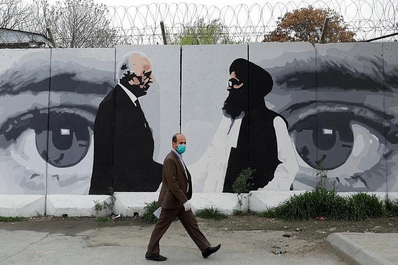 An Afghan man walking past a wall painted with a photograph of the US special envoy for Afghan reconciliation, Mr Zalmay Khalilzad (left), and Taleban political chief Mullah Abdul Ghani Baradar, in Kabul, Afghanistan.