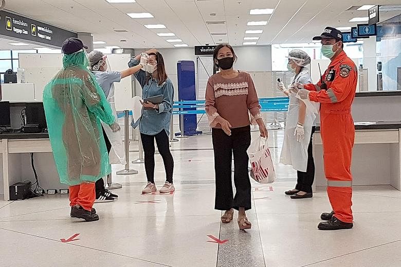 ST reporter Tan Hui Yee on an almost empty flight from the Thai capital Bangkok to the north-eastern province of Ubon Ratchathani. From left: An attendant on the one-hour flight from Bangkok to Ubon Ratchathani wearing disposable plastic overalls on 