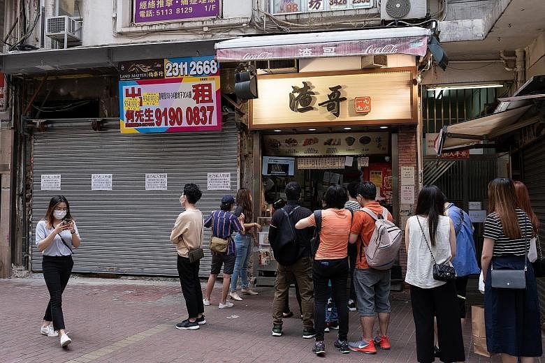 Customers lining up at a food outlet, while another one remains shut, in Hong Kong. Private consumption expenditure fell 10.2 per cent in the first quarter from a year earlier as social distancing measures brought consumption-related activities to a 