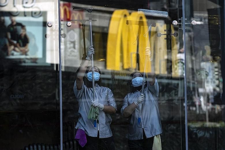 Above: Workers cleaning a shop's glass panel in Kuala Lumpur yesterday, when the Malaysian government allowed certain economic and social activities in the country to resume after 47 days of a movement control order. Right: Seats in a train marked ou