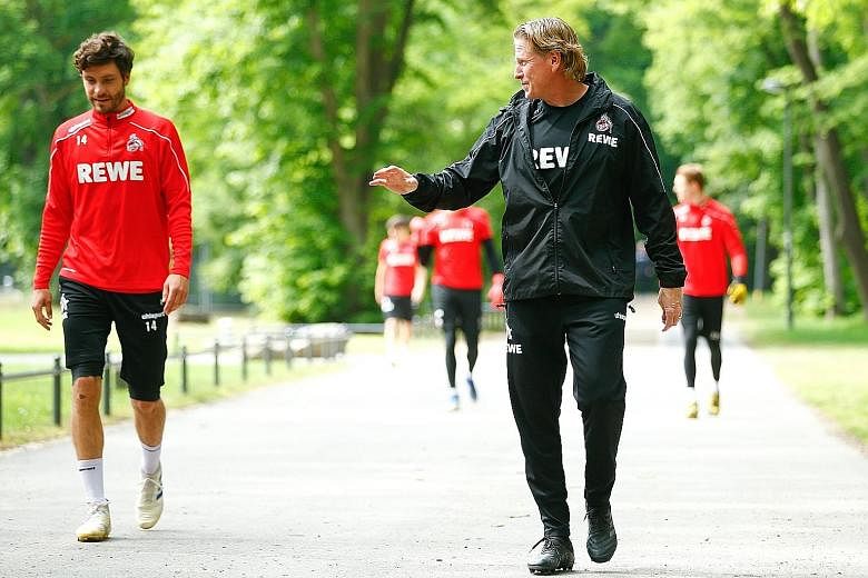 Cologne captain Jonas Hector and coach Markus Gisdol keeping their distance as they head to the training ground yesterday. PHOTO: REUTERS